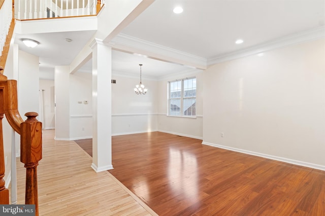 empty room featuring light wood-type flooring, crown molding, and a notable chandelier