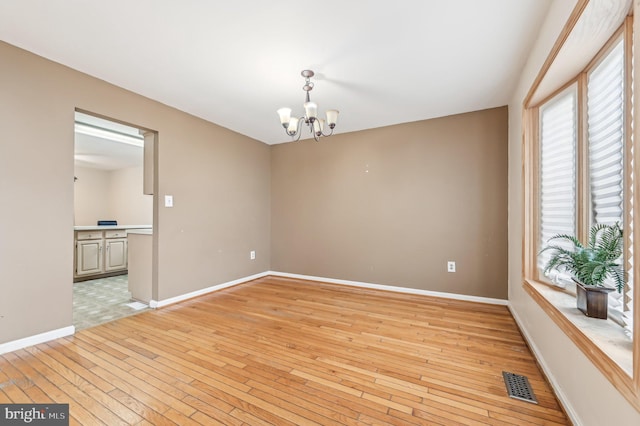 empty room with an inviting chandelier and light wood-type flooring