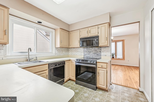 kitchen with light brown cabinets, backsplash, black appliances, sink, and light hardwood / wood-style flooring