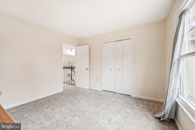 unfurnished bedroom with a closet and light colored carpet