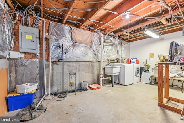 basement featuring washing machine and clothes dryer, electric panel, and sink