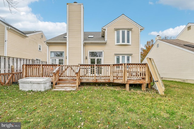 rear view of property featuring a deck and a lawn