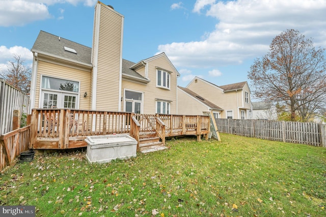 rear view of house with a wooden deck and a lawn