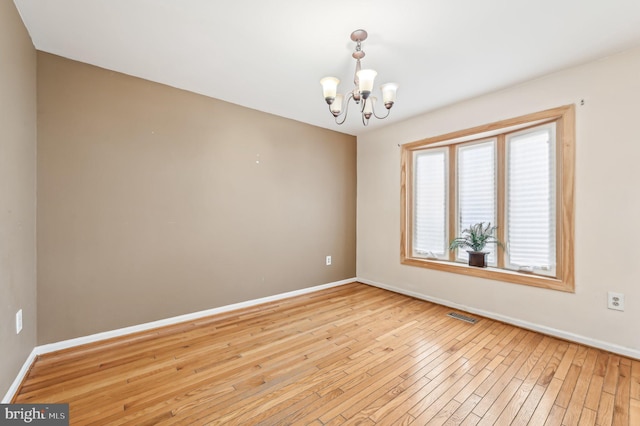 unfurnished room with light hardwood / wood-style flooring and a notable chandelier