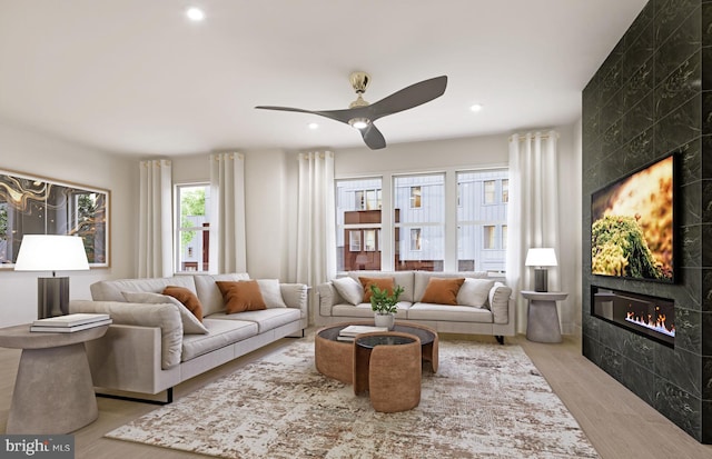 living room with a fireplace, ceiling fan, and light wood-type flooring