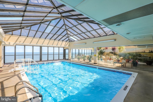 view of swimming pool with a lanai, a water view, and a patio