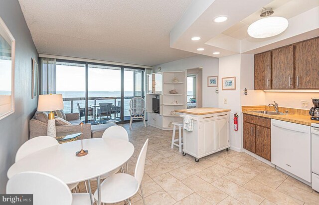 kitchen featuring sink, wooden counters, a textured ceiling, white appliances, and light tile patterned flooring