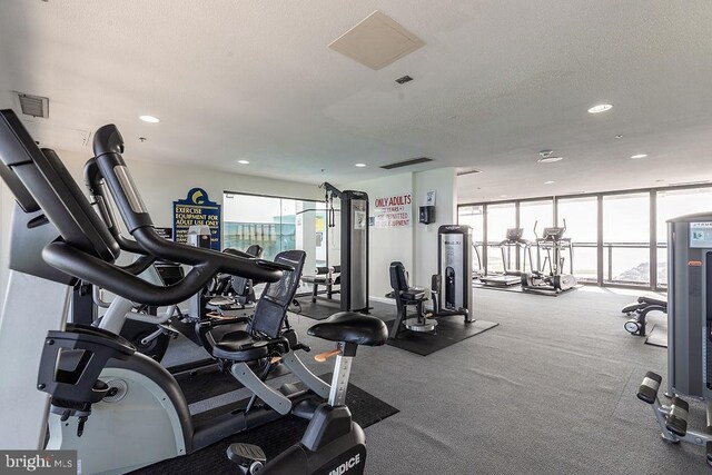 gym with a textured ceiling and floor to ceiling windows