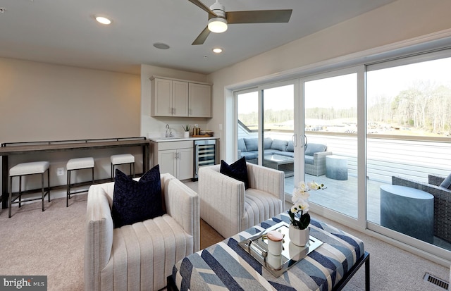 living room with wet bar, light carpet, beverage cooler, and ceiling fan