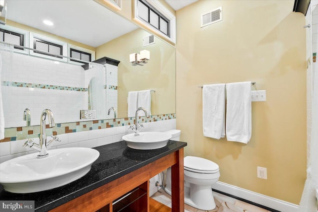 bathroom featuring decorative backsplash, vanity, toilet, and walk in shower