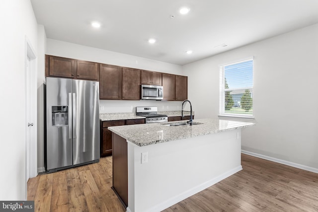 kitchen featuring a center island with sink, light wood-type flooring, sink, and appliances with stainless steel finishes