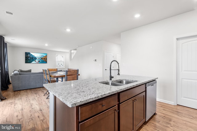 kitchen featuring dishwasher, light wood-type flooring, a center island with sink, and sink