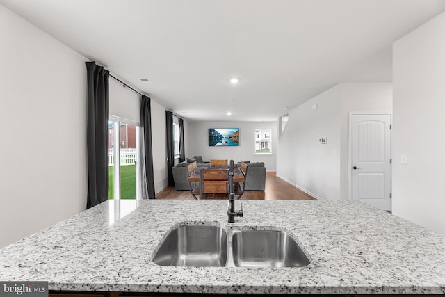 kitchen featuring a center island with sink, light stone counters, a wealth of natural light, and sink