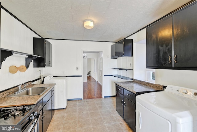 kitchen featuring light wood-type flooring, a textured ceiling, sink, stainless steel range with gas stovetop, and independent washer and dryer