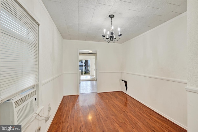 empty room featuring hardwood / wood-style floors, a notable chandelier, and ornamental molding