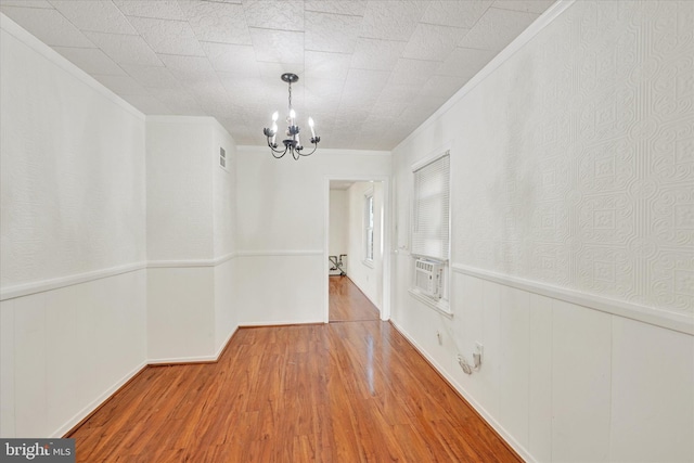 unfurnished dining area featuring a chandelier, hardwood / wood-style flooring, ornamental molding, and cooling unit