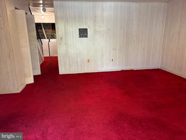 spare room with separate washer and dryer, wooden walls, and dark carpet