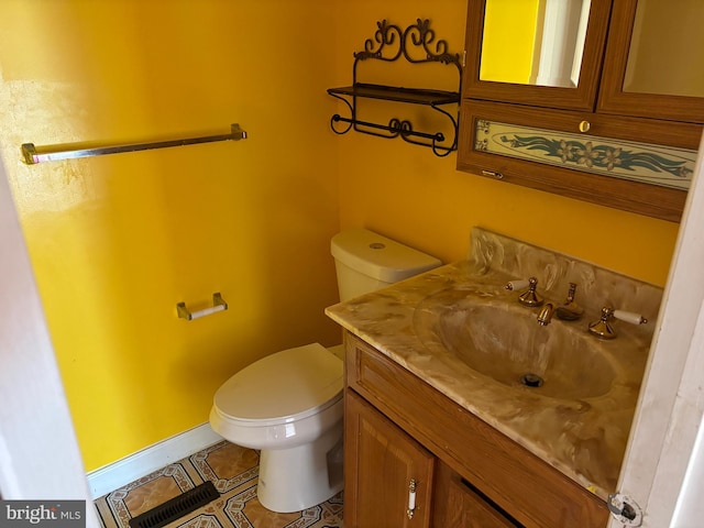 bathroom with toilet, vanity, and tile patterned floors