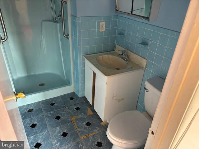 bathroom featuring tile walls, walk in shower, toilet, and vanity