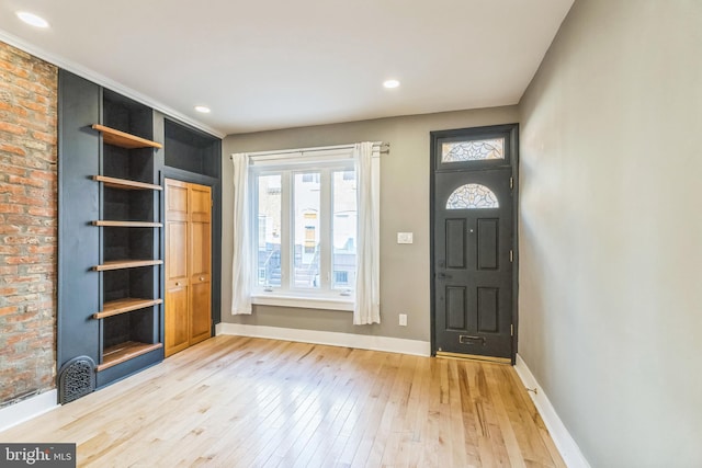 foyer with brick wall and light hardwood / wood-style floors