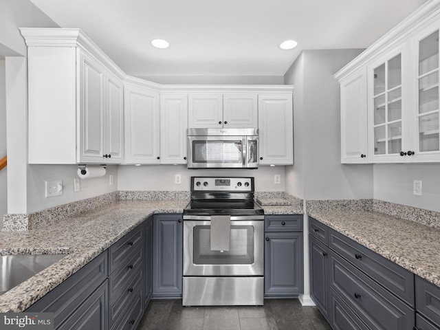 kitchen featuring white cabinetry, dark hardwood / wood-style flooring, light stone counters, and appliances with stainless steel finishes