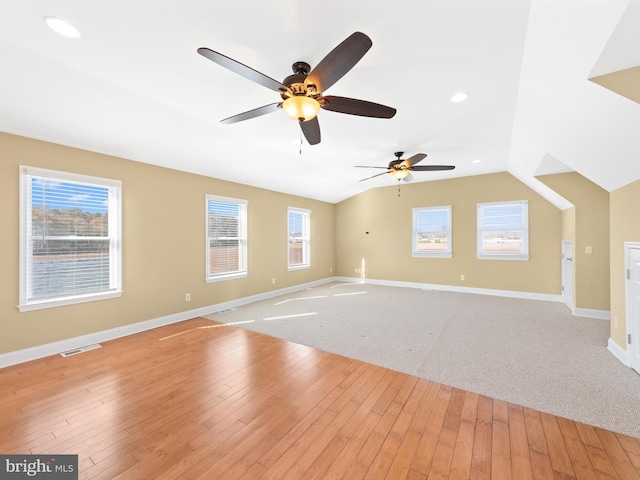 unfurnished living room featuring light hardwood / wood-style flooring, vaulted ceiling, ceiling fan, and a healthy amount of sunlight