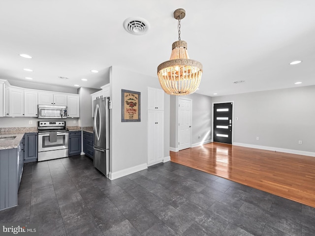 kitchen featuring light stone countertops, appliances with stainless steel finishes, dark wood-type flooring, pendant lighting, and white cabinetry