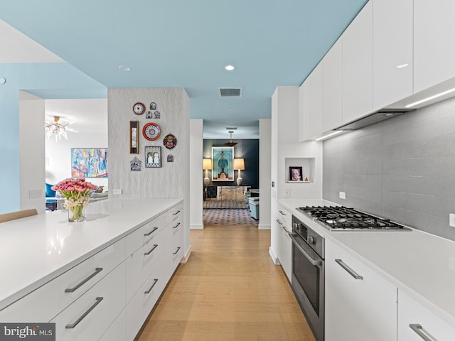 kitchen with decorative backsplash, light wood-type flooring, stainless steel appliances, ceiling fan, and white cabinetry