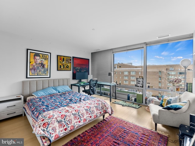 bedroom with expansive windows and light wood-type flooring