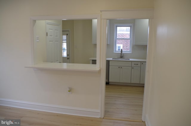 kitchen with white cabinetry, sink, and light wood-type flooring