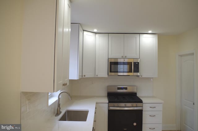 kitchen with white cabinetry, sink, backsplash, and stainless steel appliances