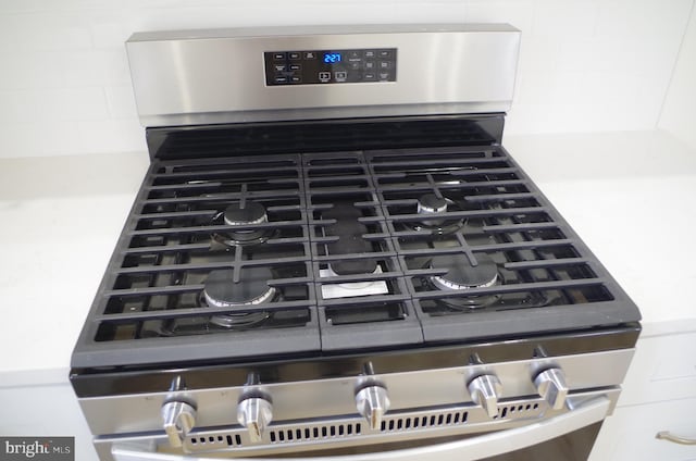 interior details with backsplash and stainless steel range with gas cooktop