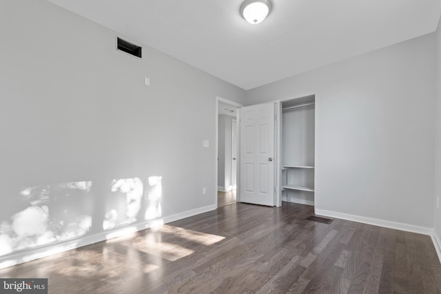 unfurnished bedroom featuring a closet and dark wood-type flooring