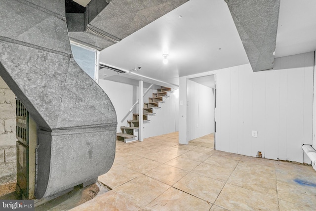 basement with tile patterned flooring and wood walls