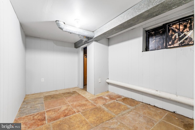 basement featuring wooden walls