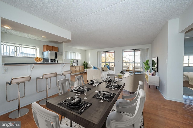 dining space with hardwood / wood-style floors and a textured ceiling