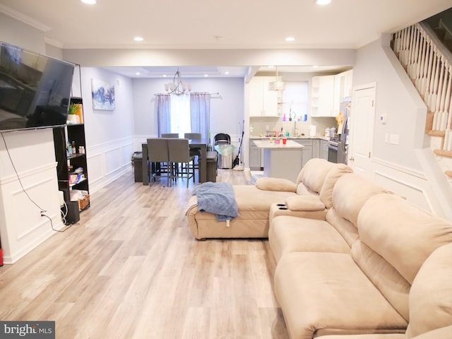 living room with crown molding, light hardwood / wood-style flooring, and an inviting chandelier