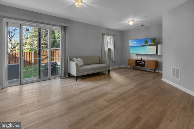 living room featuring baseboards, visible vents, and wood finished floors