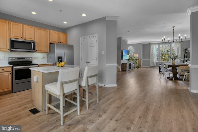 kitchen with a kitchen island, light countertops, a notable chandelier, stainless steel appliances, and recessed lighting