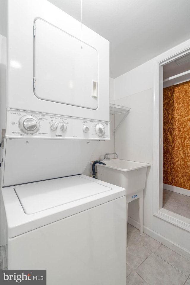 clothes washing area featuring stacked washer / drying machine and light tile patterned floors