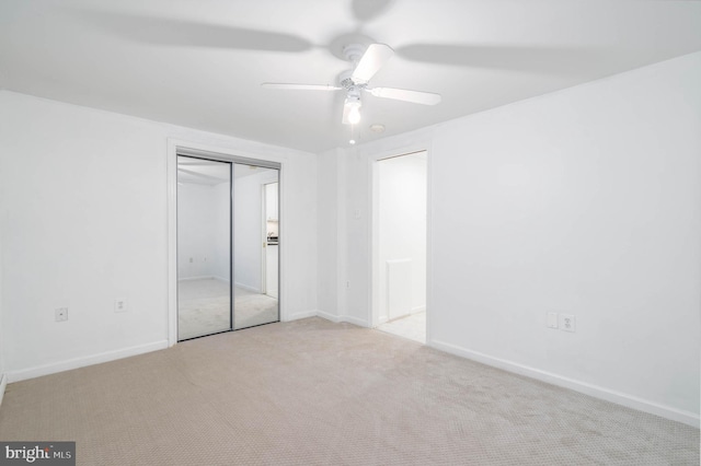 unfurnished bedroom featuring ceiling fan, light carpet, and a closet