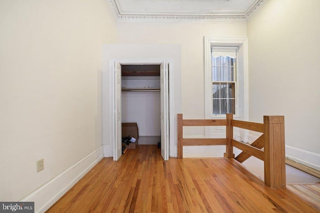 hallway with light wood-type flooring and ornamental molding