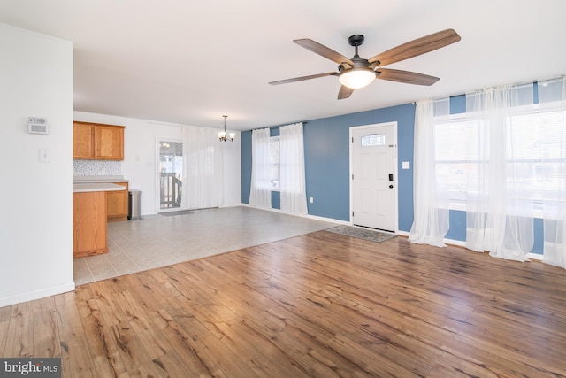 unfurnished living room with light hardwood / wood-style floors and ceiling fan with notable chandelier