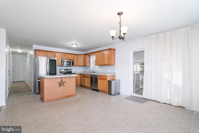 kitchen with pendant lighting, a center island, decorative backsplash, a notable chandelier, and stainless steel appliances