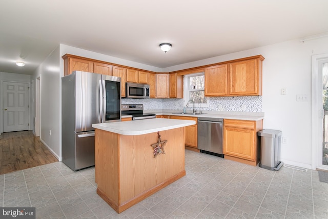 kitchen featuring appliances with stainless steel finishes, a kitchen breakfast bar, tasteful backsplash, sink, and a center island