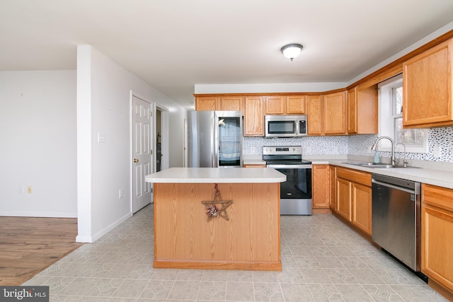 kitchen featuring decorative backsplash, appliances with stainless steel finishes, sink, a center island, and light hardwood / wood-style floors