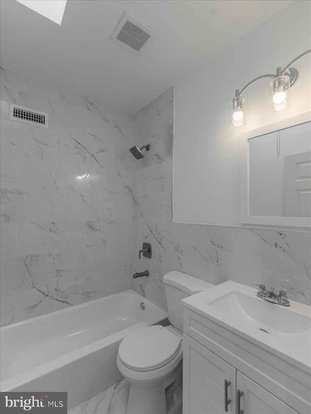 full bathroom with tiled shower / bath combo, toilet, tile walls, and vanity