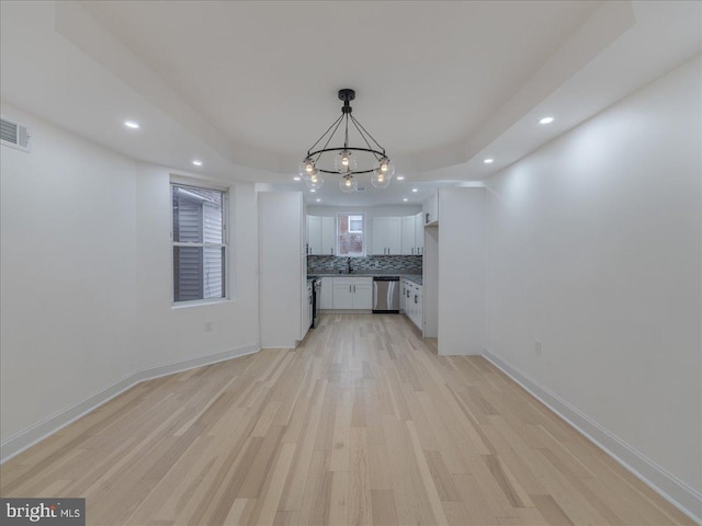 unfurnished living room with light wood-type flooring and a notable chandelier