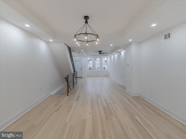 unfurnished living room featuring light hardwood / wood-style flooring and ceiling fan with notable chandelier