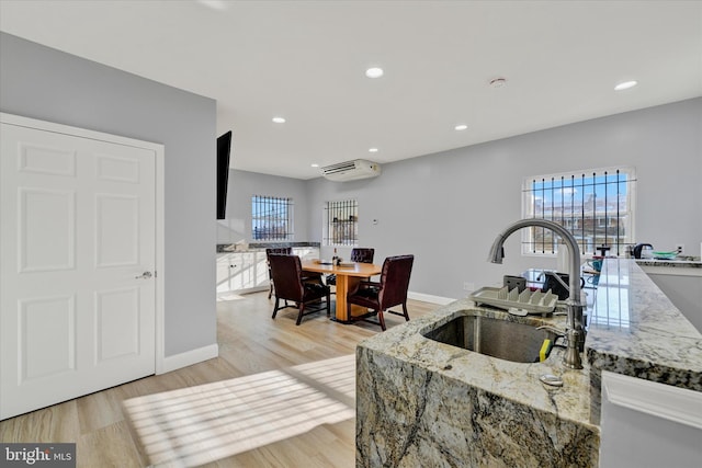 kitchen with sink, light wood-type flooring, and light stone counters